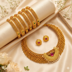 Studio display of gold plated Maharashtrian thushi choker necklace with crescent ruby pendant, pearl drops, round stud earrings, and 6 mesh bangles on ivory fabric.