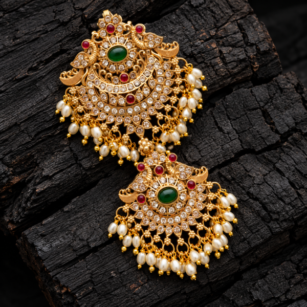 Double peacock Rakodi Jada Billa hair accessory with green centre stones, ruby-red accents, white stones and pearl-like bead drops on black wood.